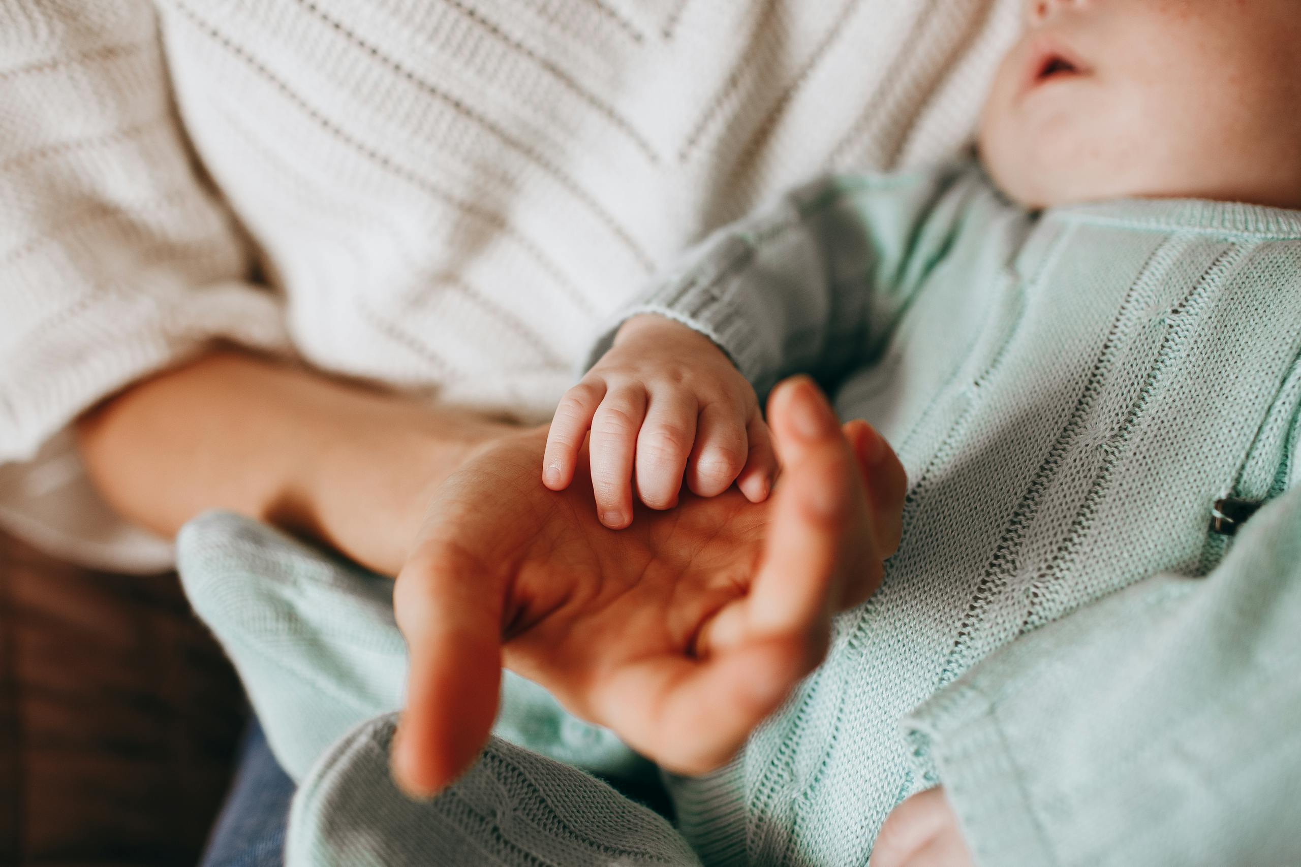 Intimate close-up of a mother holding her baby's hand, highlighting a tender moment.