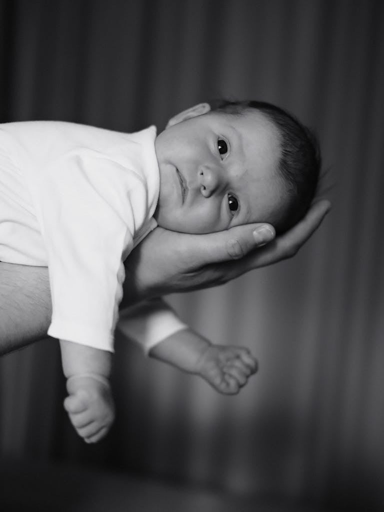 Emotional black and white photo of a newborn baby supported by a loving hand.